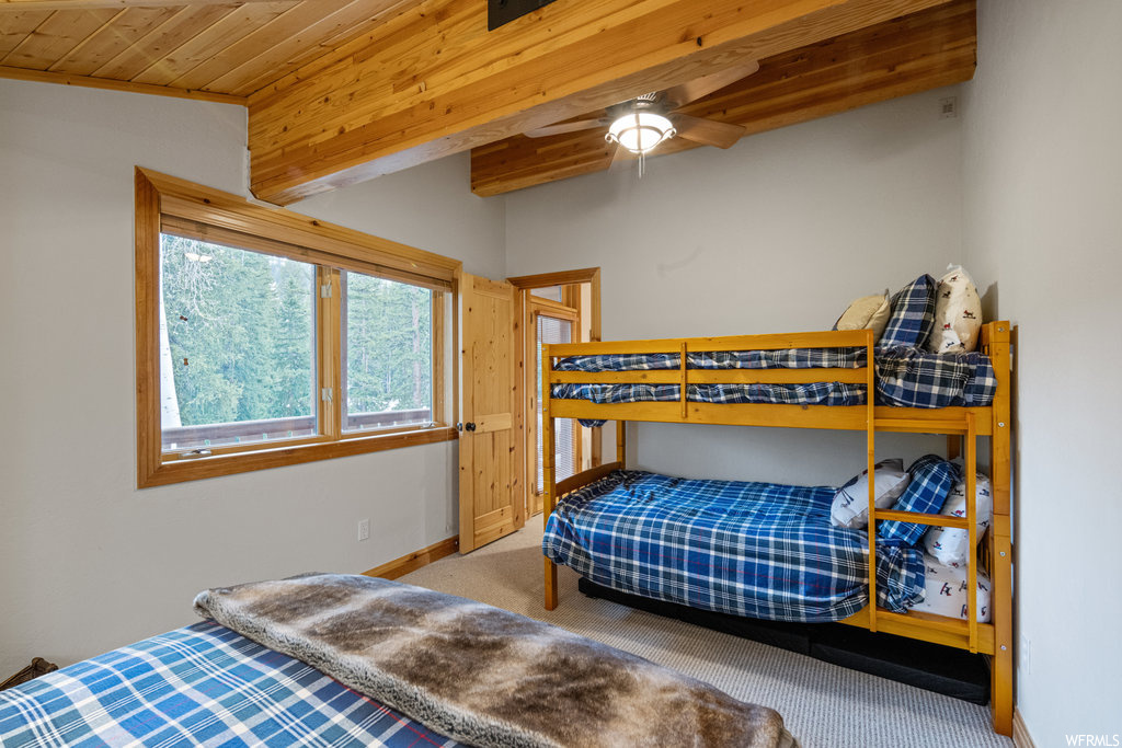 Bedroom featuring a ceiling fan, natural light, wood beam ceiling, and carpet