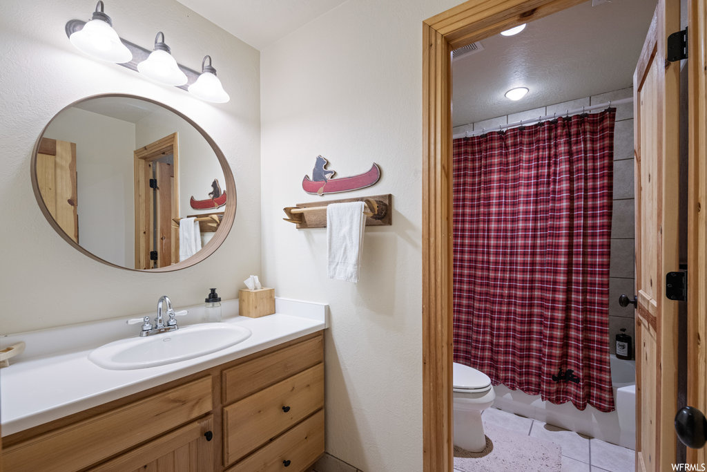 Full bathroom featuring tile floors, vanity, shower curtain, shower / washtub combination, mirror, and toilet