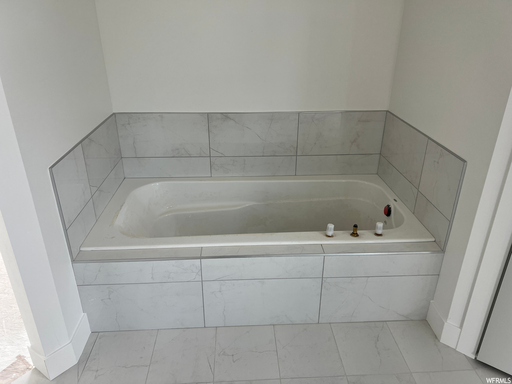 Bathroom featuring tiled bath and light tile floors