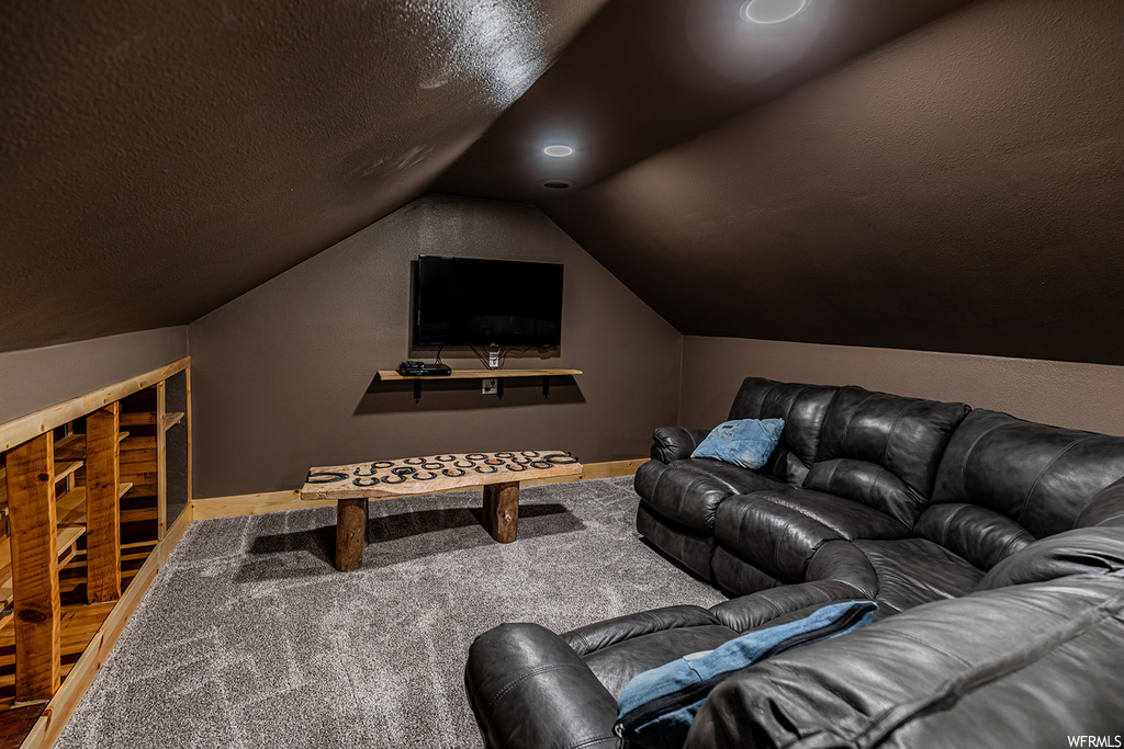 Home theater room with lofted ceiling and TV