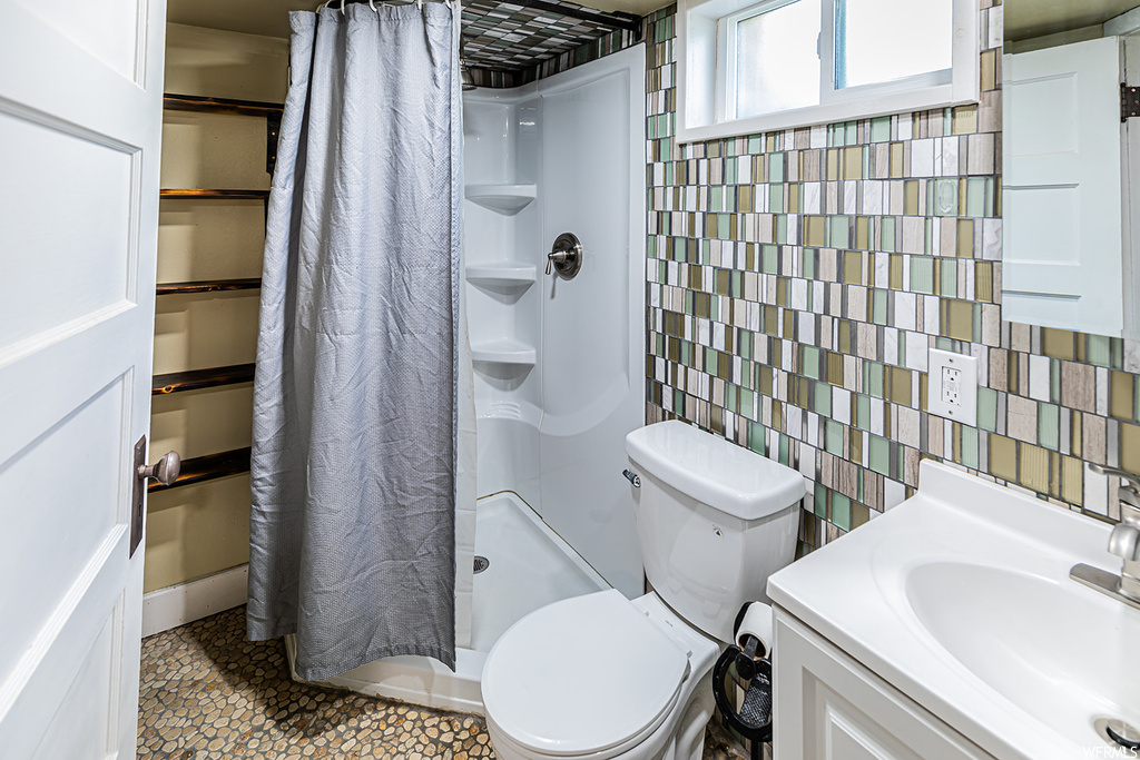 Bathroom featuring large vanity, toilet, shower curtain, mirror, and a shower