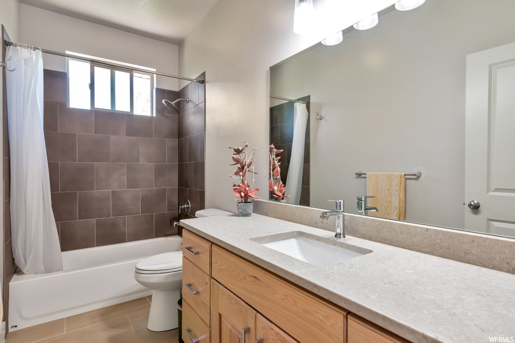 Full bathroom featuring natural light, tile floors, mirror, shower curtain, toilet, bathing tub / shower combination, and vanity