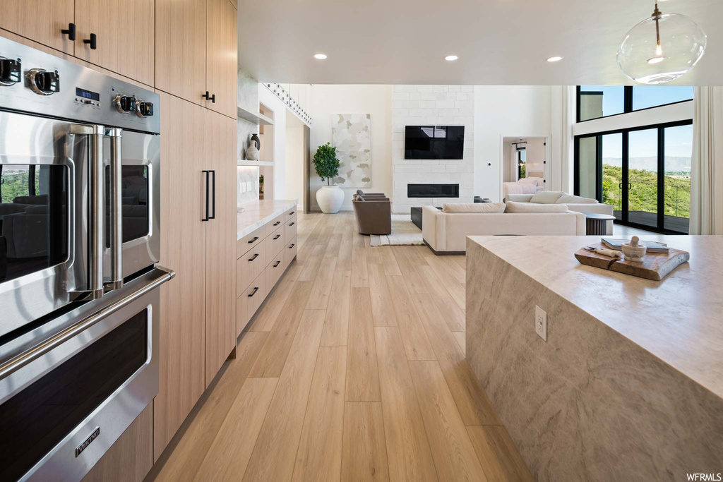 Kitchen featuring natural light, TV, oven, light countertops, pendant lighting, and light floors