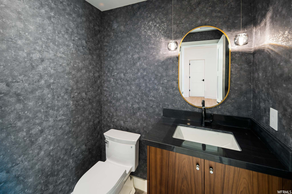 Half bathroom with mirror, vanity, and toilet