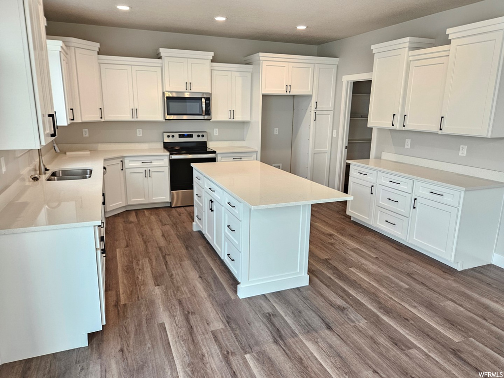 Kitchen featuring a kitchen island, white cabinets, stainless steel appliances, and dark hardwood floors