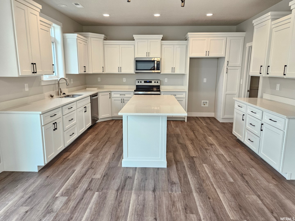 Kitchen with a kitchen island, dark hardwood flooring, stainless steel appliances, and sink