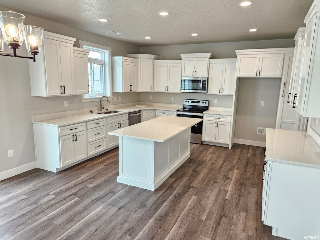 Kitchen featuring dark hardwood flooring, pendant lighting, stainless steel appliances, and a center island
