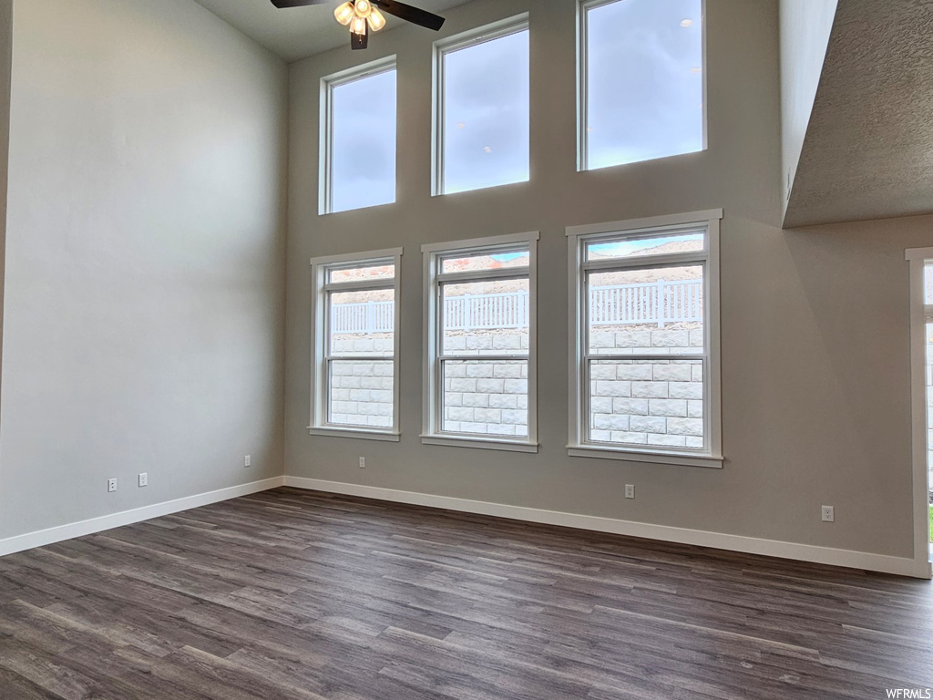 Empty room featuring dark hardwood floors, vaulted ceiling high, and ceiling fan