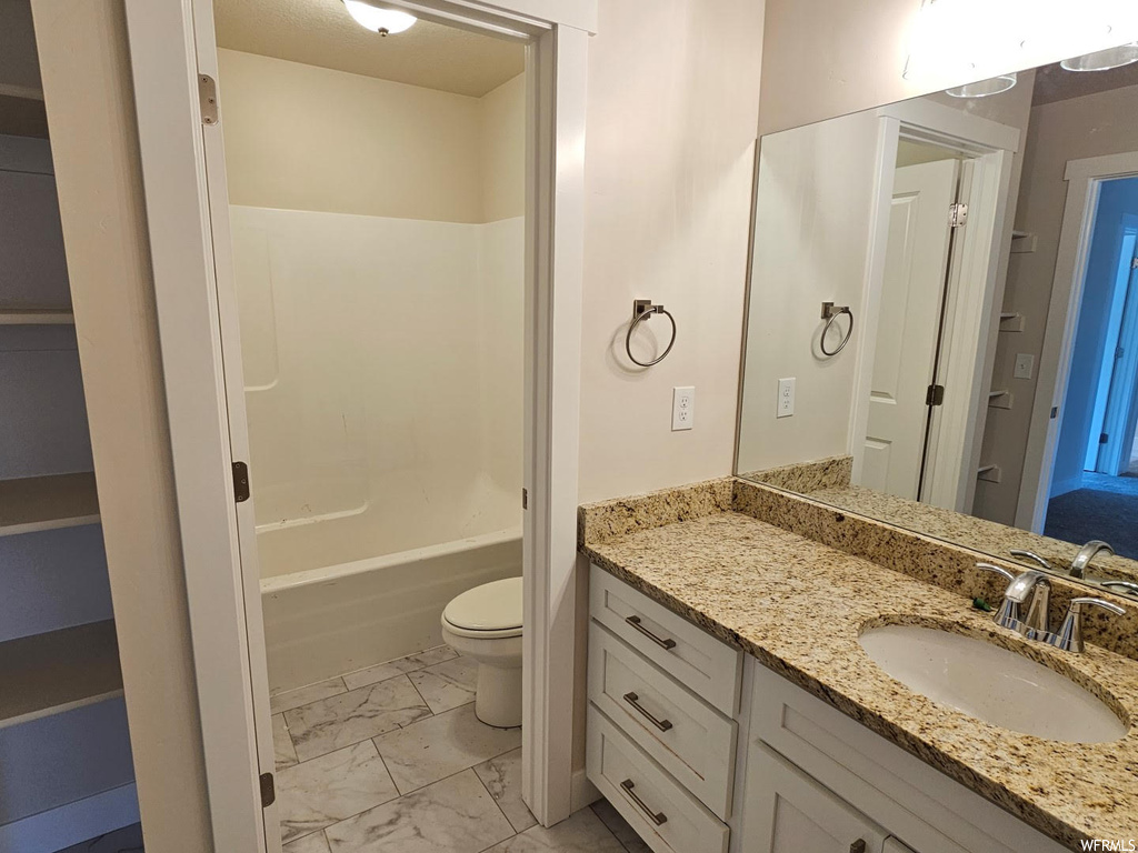 Full bathroom featuring tile floors, mirror, shower / tub combination, vanity, and toilet
