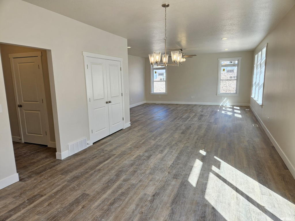 Hardwood floored empty room featuring natural light and a ceiling fan