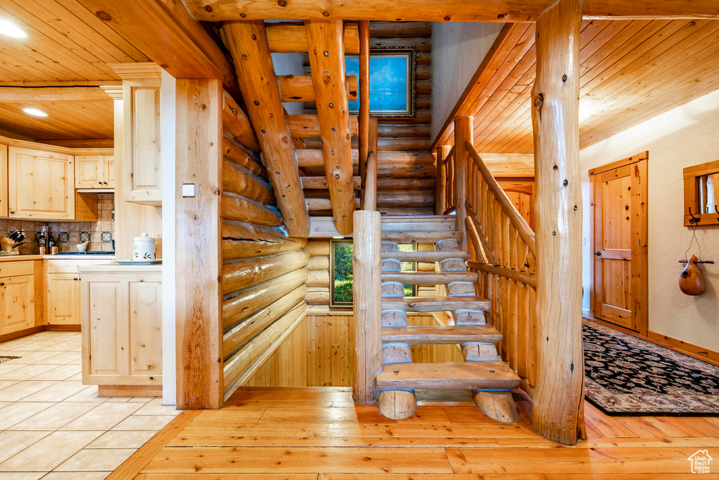 Stairs featuring rustic walls, light hardwood / wood-style floors, and wooden ceiling