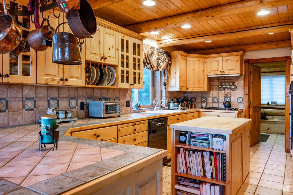 Kitchen featuring backsplash, beam ceiling, sink, and light tile floors