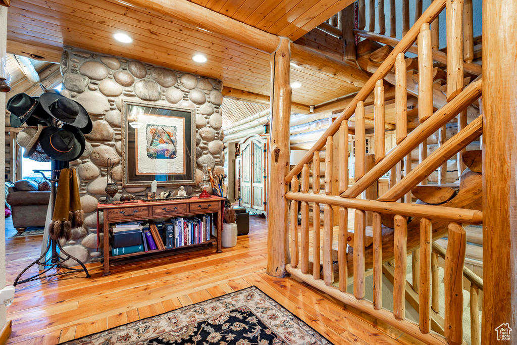 Stairs featuring log walls, wood-type flooring, beam ceiling, and wood ceiling