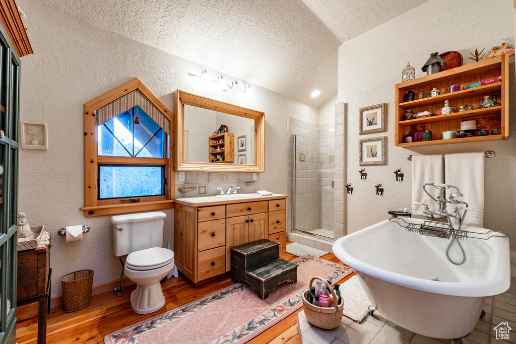 Full bathroom featuring toilet, a textured ceiling, lofted ceiling, vanity, and hardwood / wood-style floors