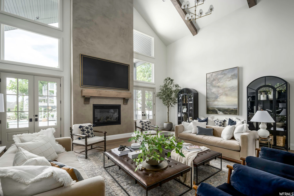 Living room featuring french doors, a high ceiling, a wealth of natural light, and TV