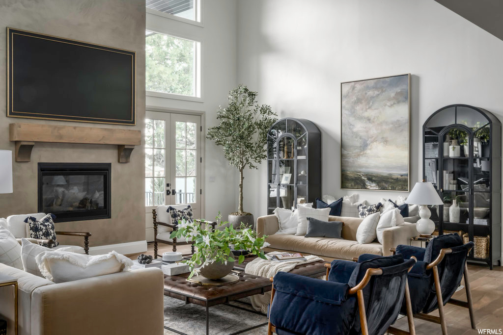 Living room featuring natural light, a fireplace, french doors, and a high ceiling