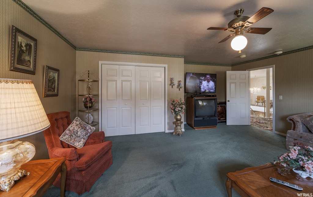 Carpeted living room featuring a ceiling fan and TV