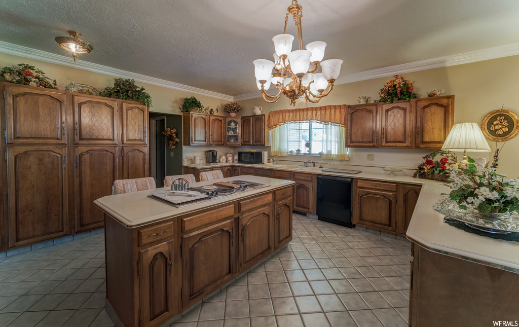 Kitchen featuring natural light, a center island, a notable chandelier, electric stovetop, dishwasher, microwave, light countertops, light tile flooring, and brown cabinets