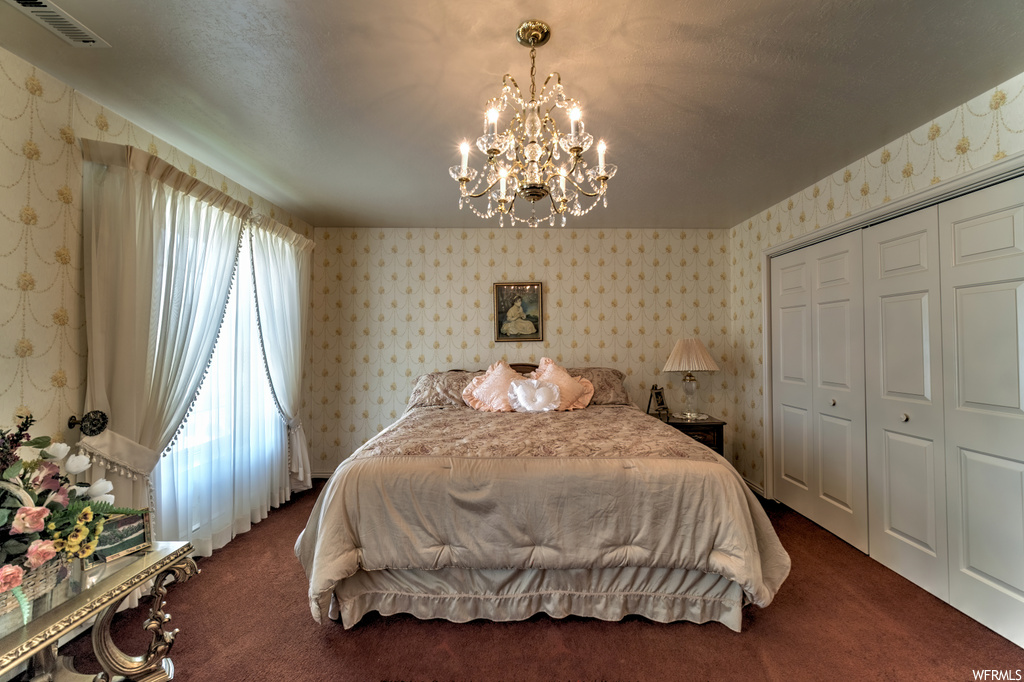 Bedroom with natural light, a notable chandelier, and carpet