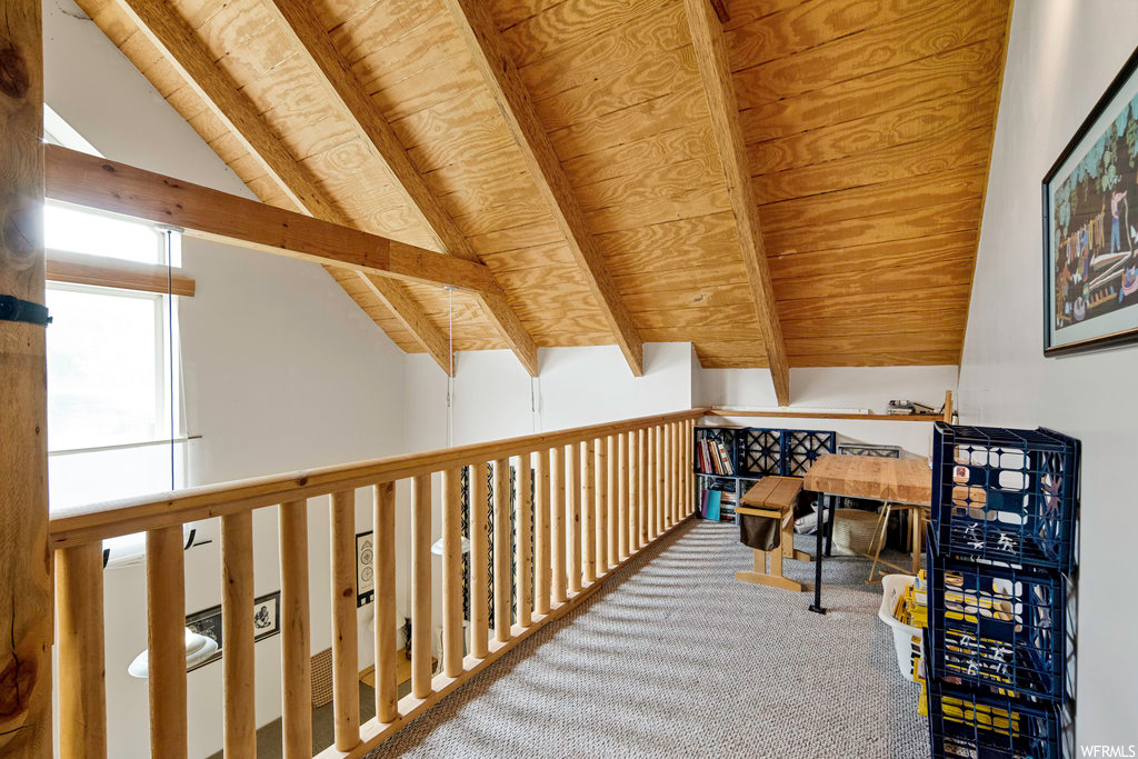Interior space featuring natural light, carpet, and lofted ceiling with beams