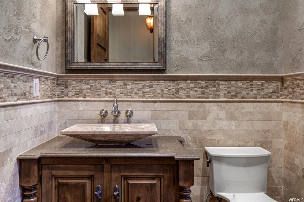 Bathroom featuring toilet, tasteful backsplash, tile walls, and vanity
