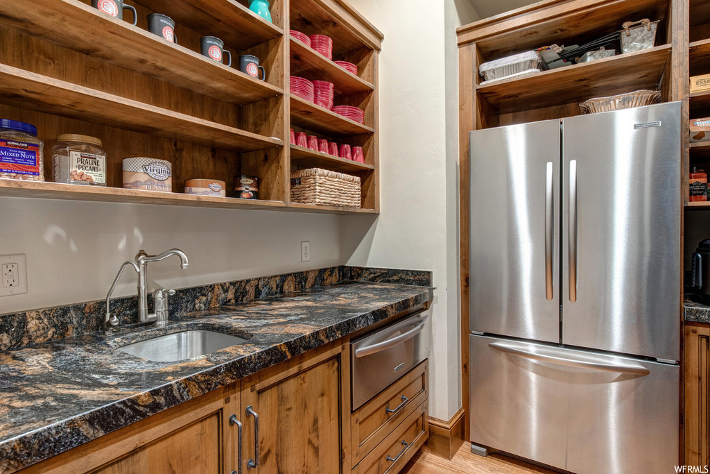 Kitchen featuring sink, light hardwood flooring, and stainless steel refrigerator