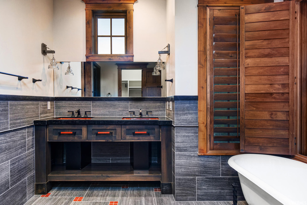 Bathroom featuring tile flooring, vanity, a bath to relax in, tile walls, and tasteful backsplash