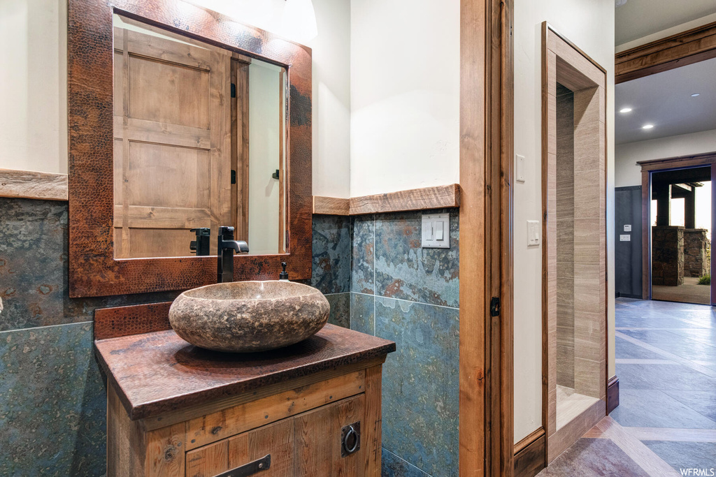 Bathroom featuring tile walls, oversized vanity, and tile flooring