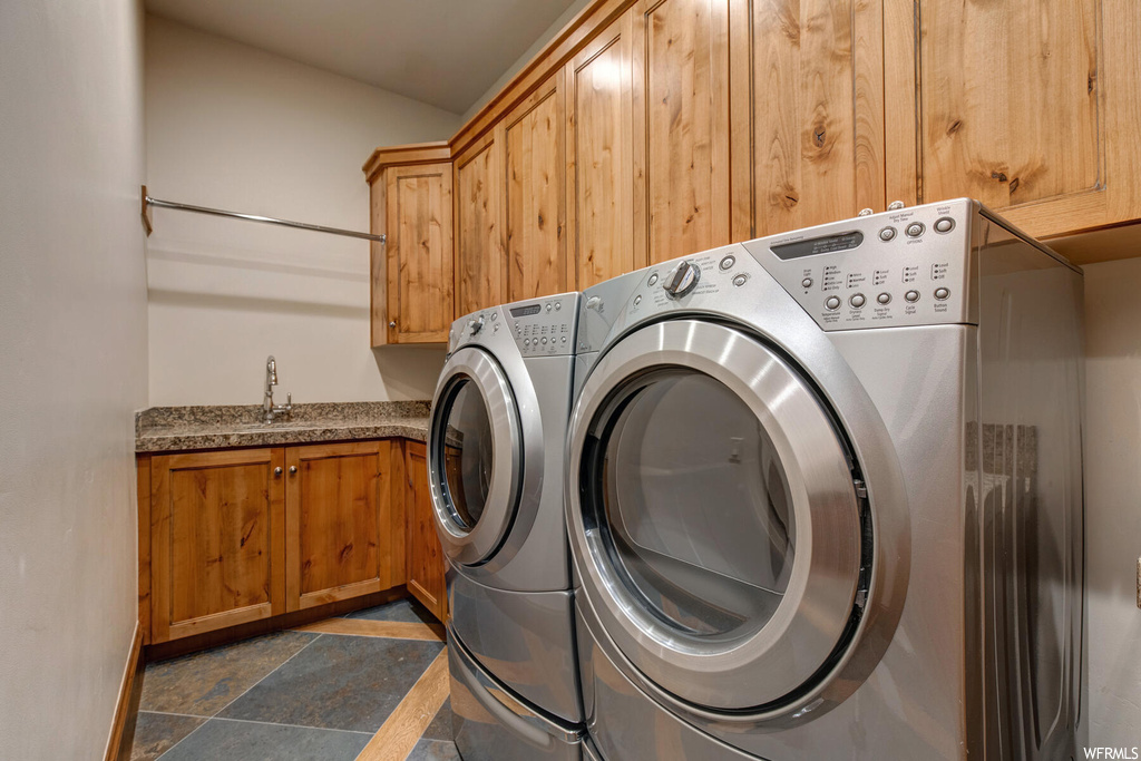 Laundry room featuring sink, independent washer and dryer, cabinets, and dark tile flooring