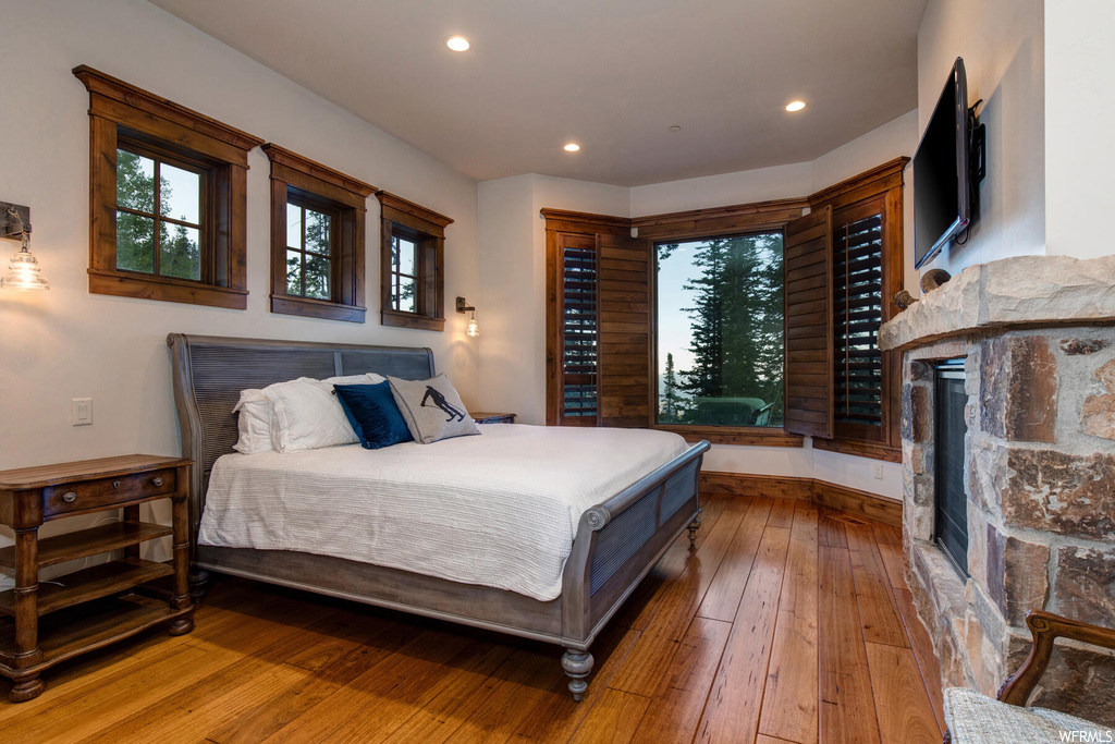 Bedroom featuring hardwood floors and a fireplace