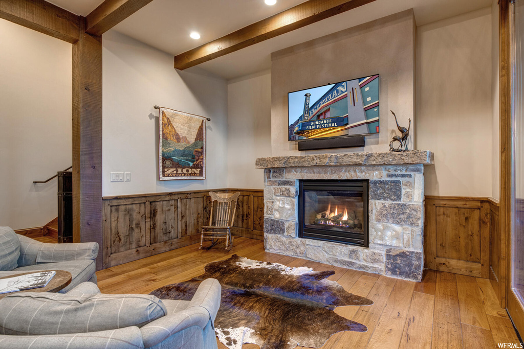 Hardwood floored living room featuring beamed ceiling and a fireplace