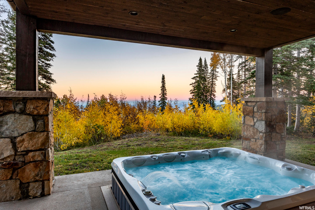 Pool at dusk with an outdoor hot tub