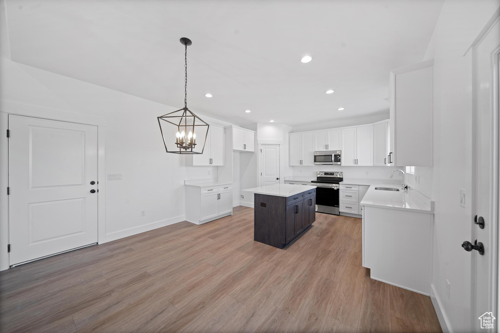 Kitchen featuring light hardwood / wood-style flooring, a center island, pendant lighting, and stainless steel appliances