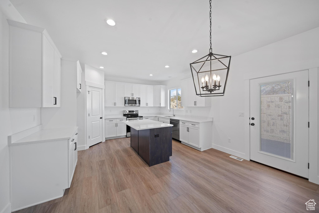 Kitchen featuring hanging light fixtures, appliances with stainless steel finishes, light wood-type flooring, and a kitchen island