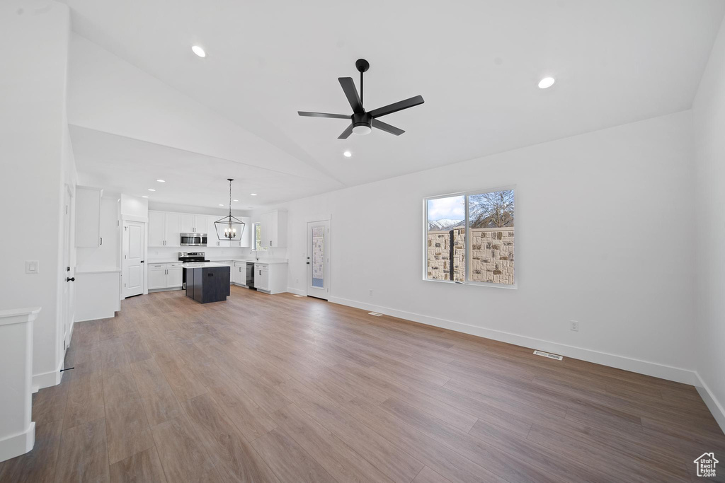 Unfurnished living room with high vaulted ceiling, wood-type flooring, and ceiling fan