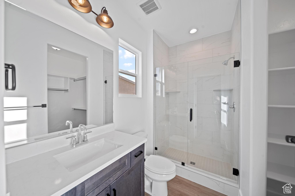Bathroom featuring hardwood / wood-style floors, vanity, toilet, and a shower with shower door