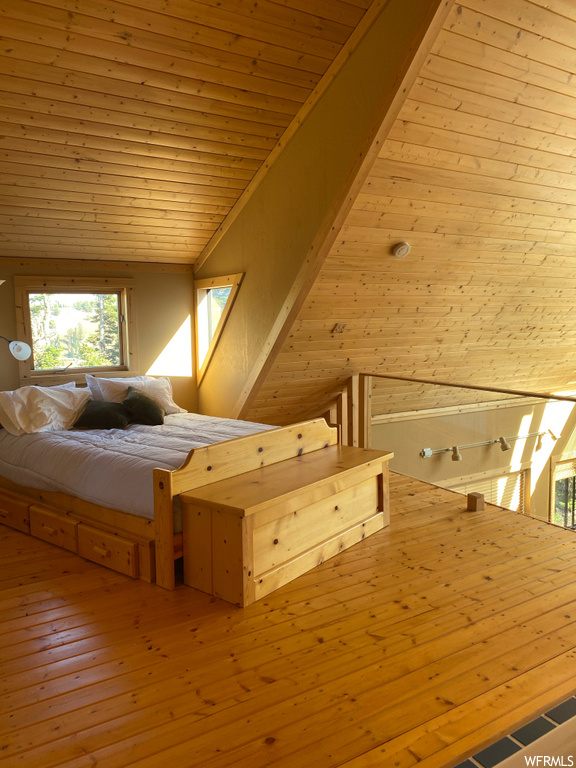 Unfurnished bedroom featuring wooden ceiling, wood walls, vaulted ceiling, and light hardwood / wood-style flooring