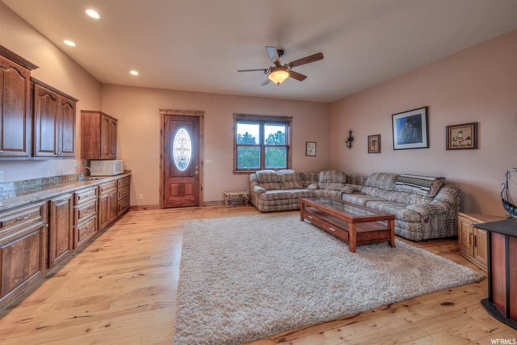 Living room featuring hardwood floors, a ceiling fan, natural light, and microwave