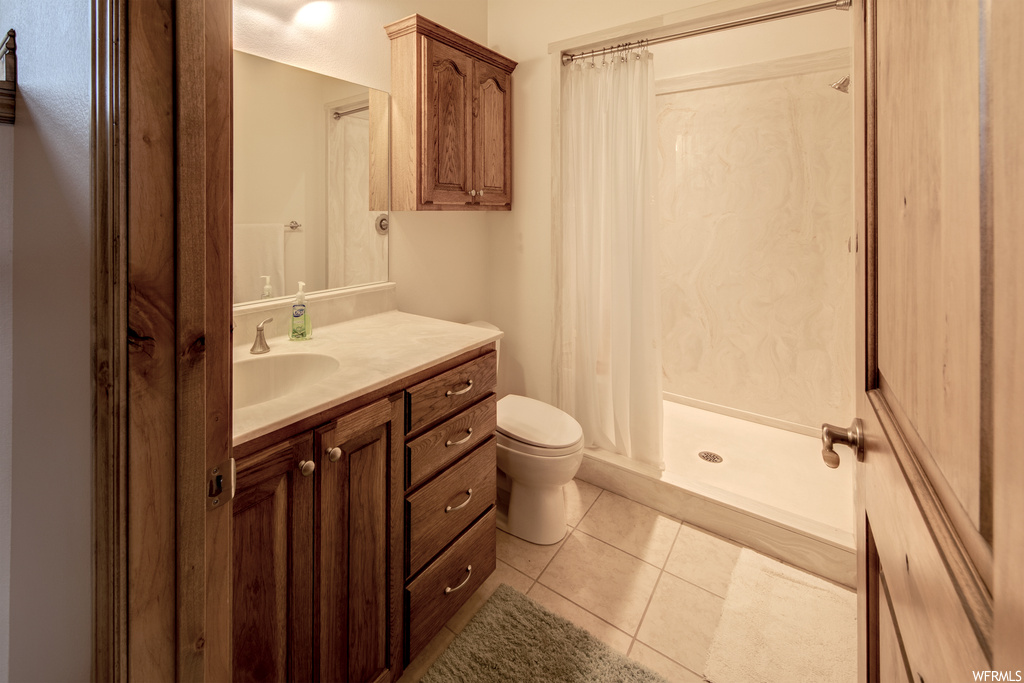 Bathroom with tile floors, mirror, toilet, a shower, shower curtain, and vanity