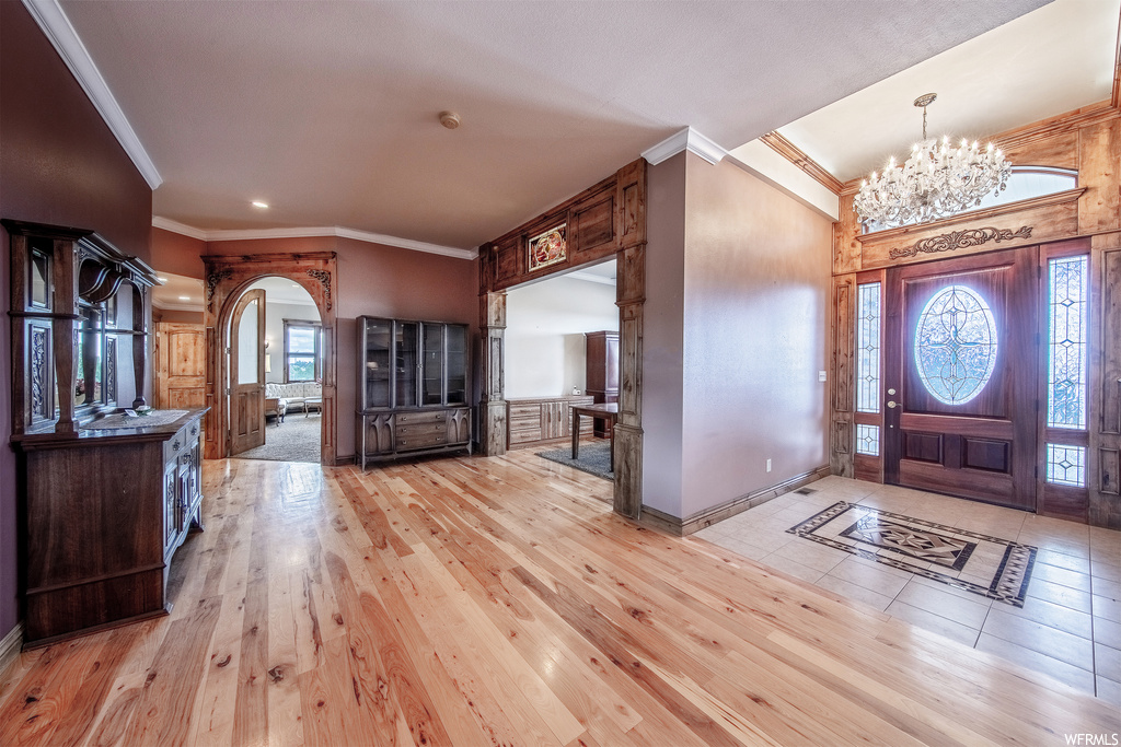Wood floored entrance foyer featuring a chandelier and natural light