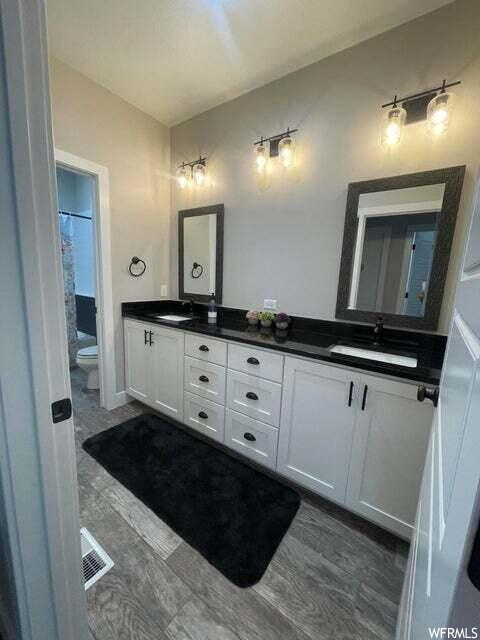 Bathroom featuring hardwood flooring, mirror, and his and hers vanity