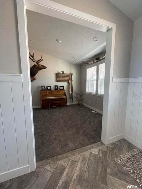Carpeted bedroom with lofted ceiling and natural light