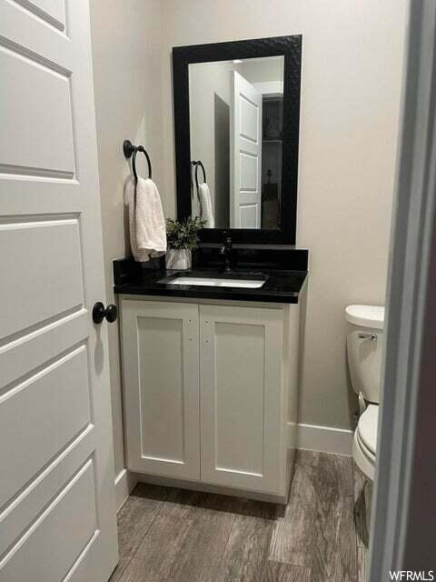 Half bath with vanity, toilet, and mirror