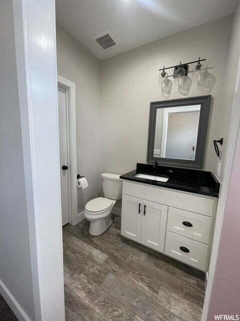 Half bathroom featuring vanity, mirror, and toilet