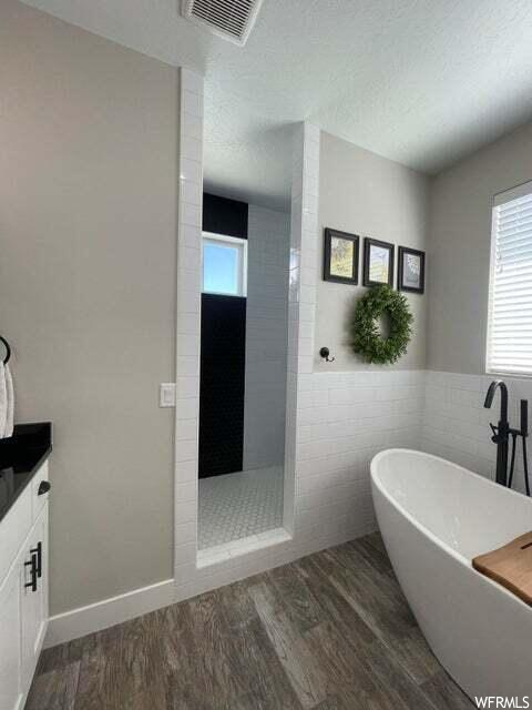 Bathroom with hardwood flooring, natural light, vanity, and separate shower and tub enclosures