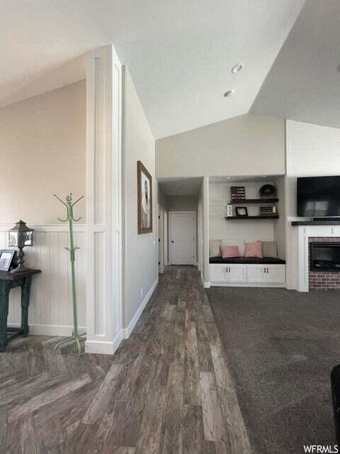 Hallway featuring lofted ceiling, hardwood flooring, and TV