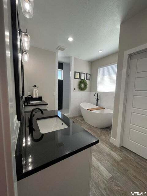 Bathroom featuring hardwood floors, natural light, and a tub