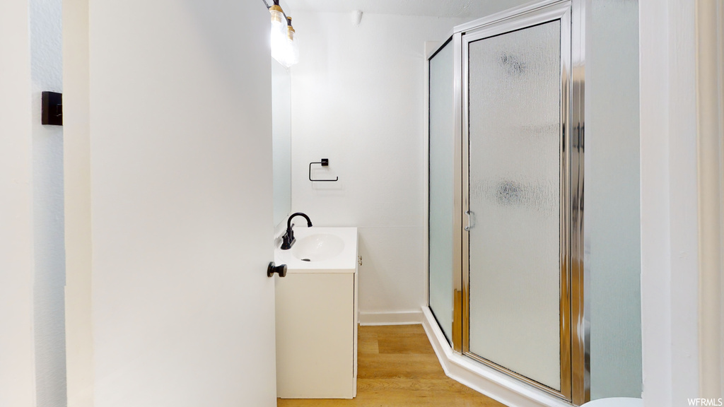 Bathroom with wood-type flooring, vanity, mirror, and enclosed shower