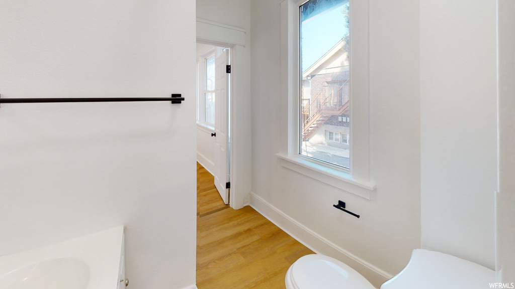 Half bath featuring hardwood floors, natural light, vanity, and toilet