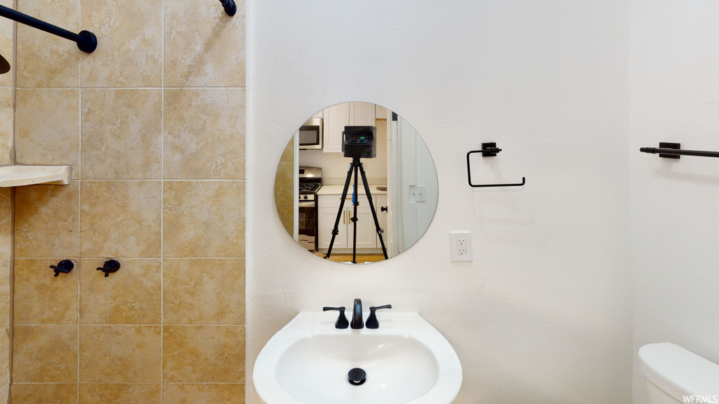 Half bath featuring microwave, mirror, washbasin, and toilet
